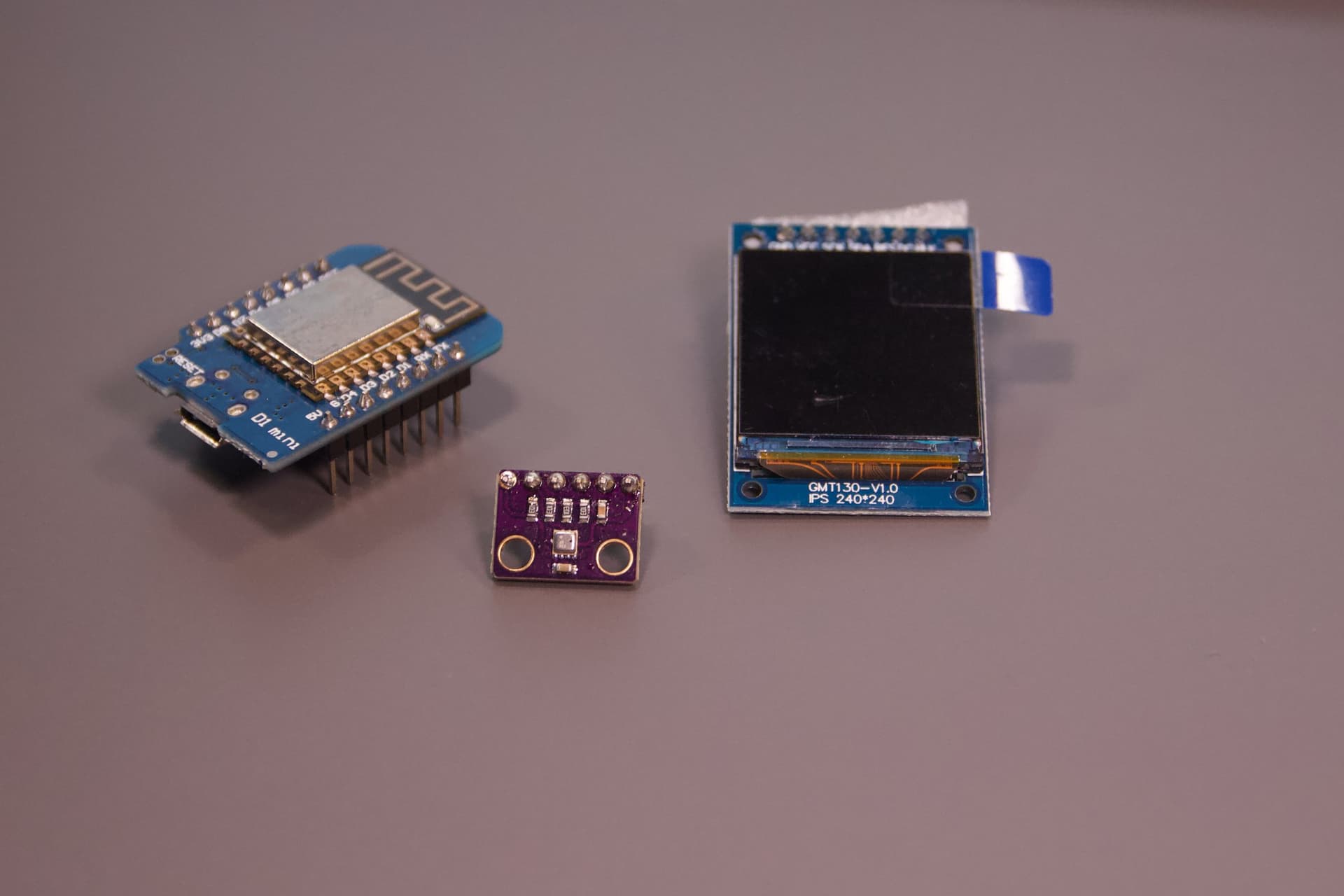 D1 Mini, violettes BME280-Sensormodul und quadratisches IPS-Display auf dem Tisch.