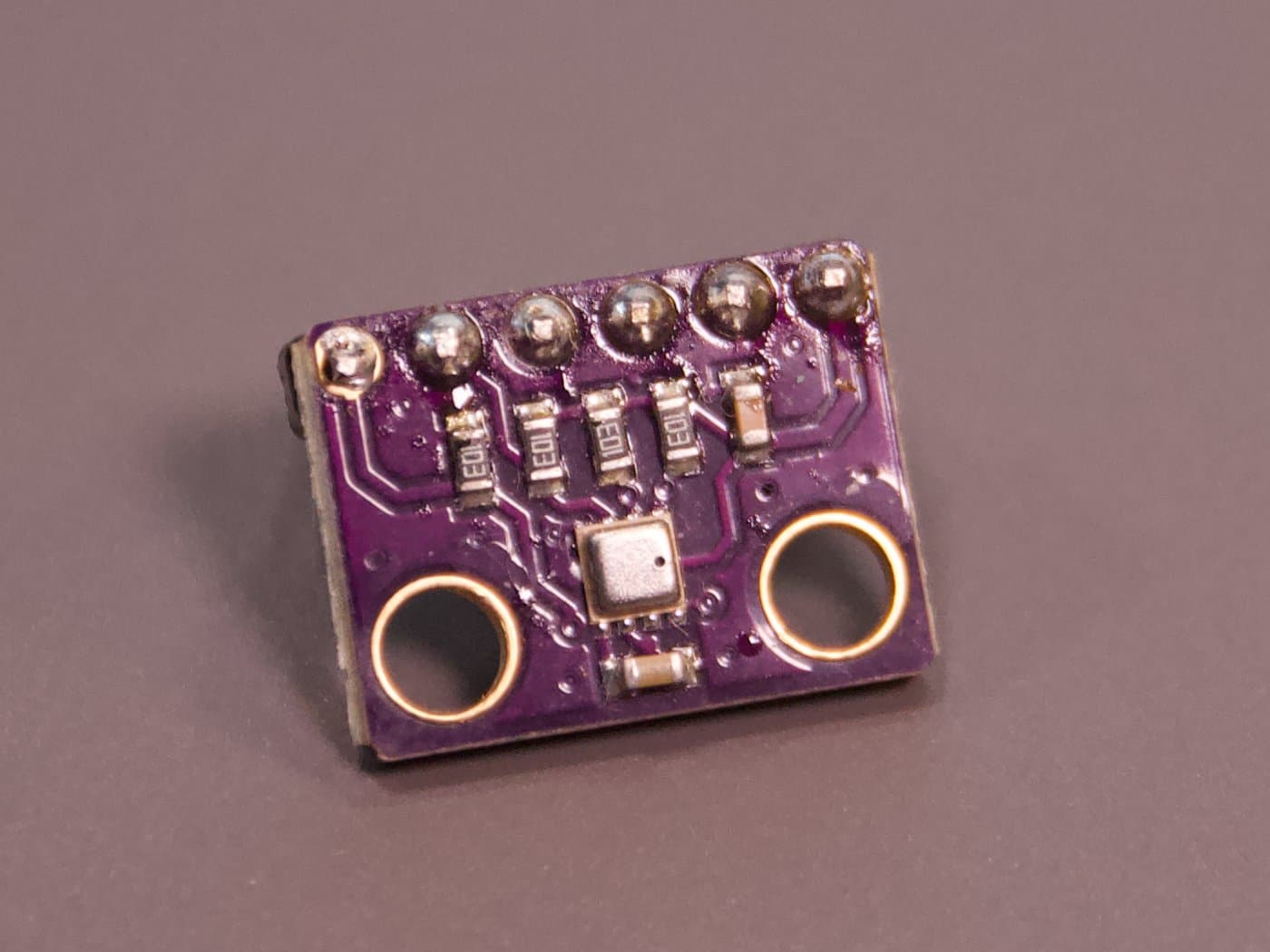 Einzelaufnahme des violetten Sensormoduls mit dem kleinen metallischen Sensor und zwei Befestigungslöchern.
