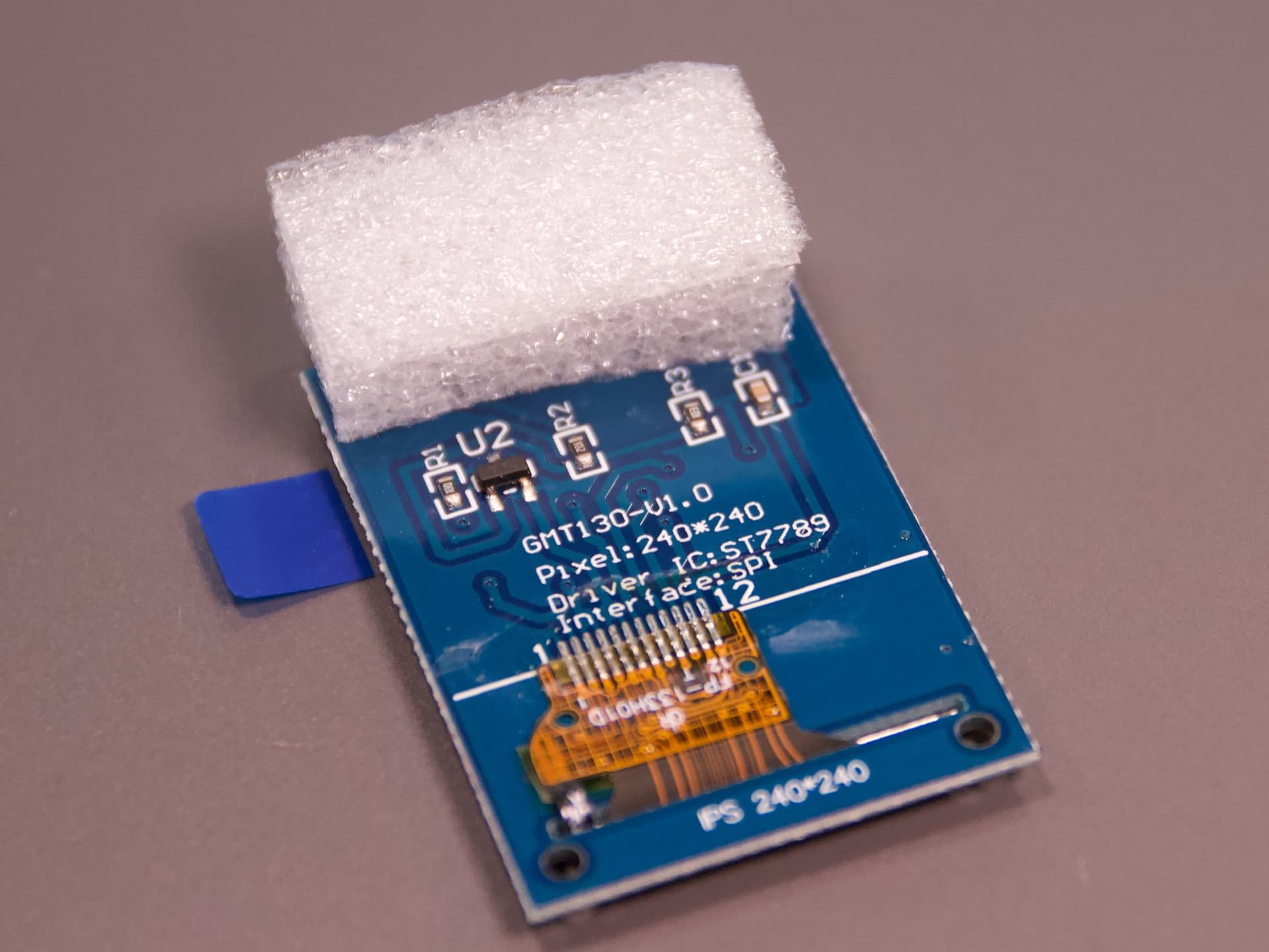 Rückseite des Displaymoduls mit den Aufdrucken GMT130-V1.0, 240 × 240 und ST7789; oben sitzt ein Schaumstoffpolster.