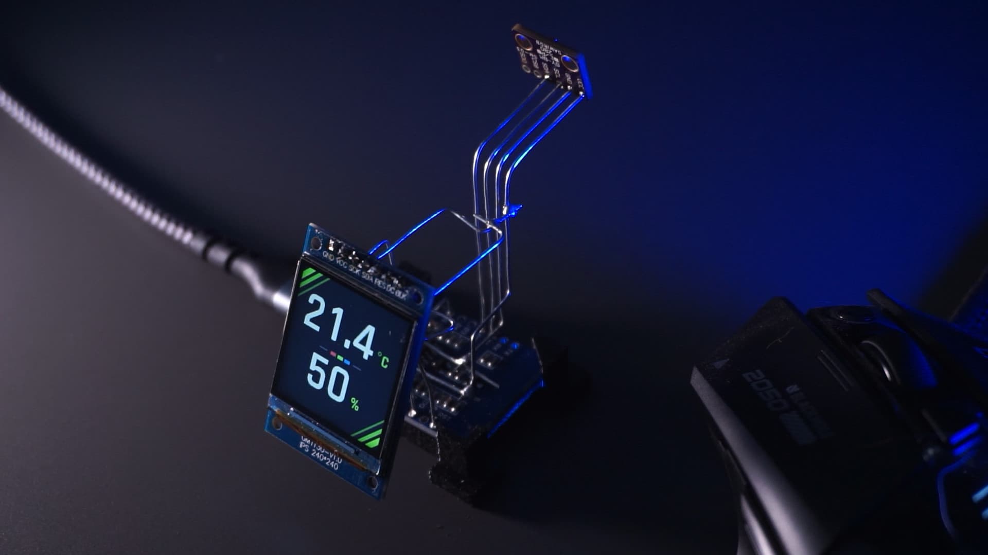 Der fertige Skinny-Temp-Aufbau schräg von oben, mit sichtbarem D1 Mini, Display und dem auf vier Drähten sitzenden Sensormodul in blauem Licht.